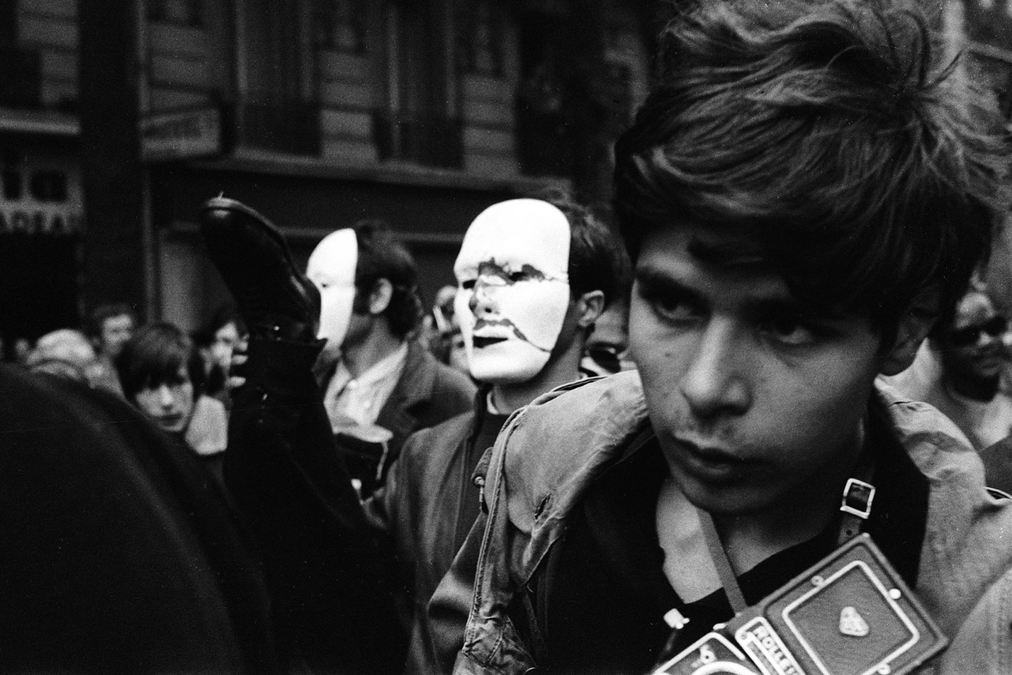 Muchacho pobre, no obstante su Rolleiflex. Entre la gente del teatro, sus ojos buscan la buena foto.